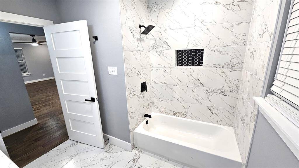 Beautiful Secondary Bathroom with Matte Black Vanity with Brushed Gold Accents and Modern LED Lighting