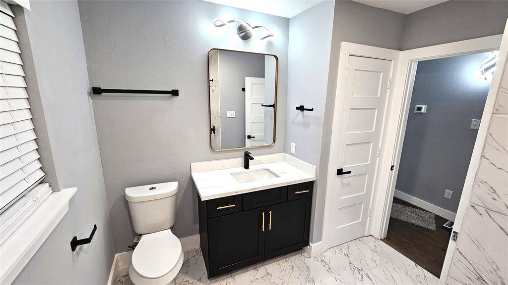 Beautiful Secondary Bathroom with Matte Black Vanity with Brushed Gold Accents and Modern LED Lighting