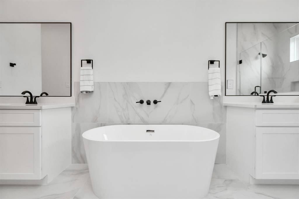 Indulge in relaxation with a spacious primary bath boasting a luxurious bathtub and double sinks with vanity and a large glass frame standing shower.