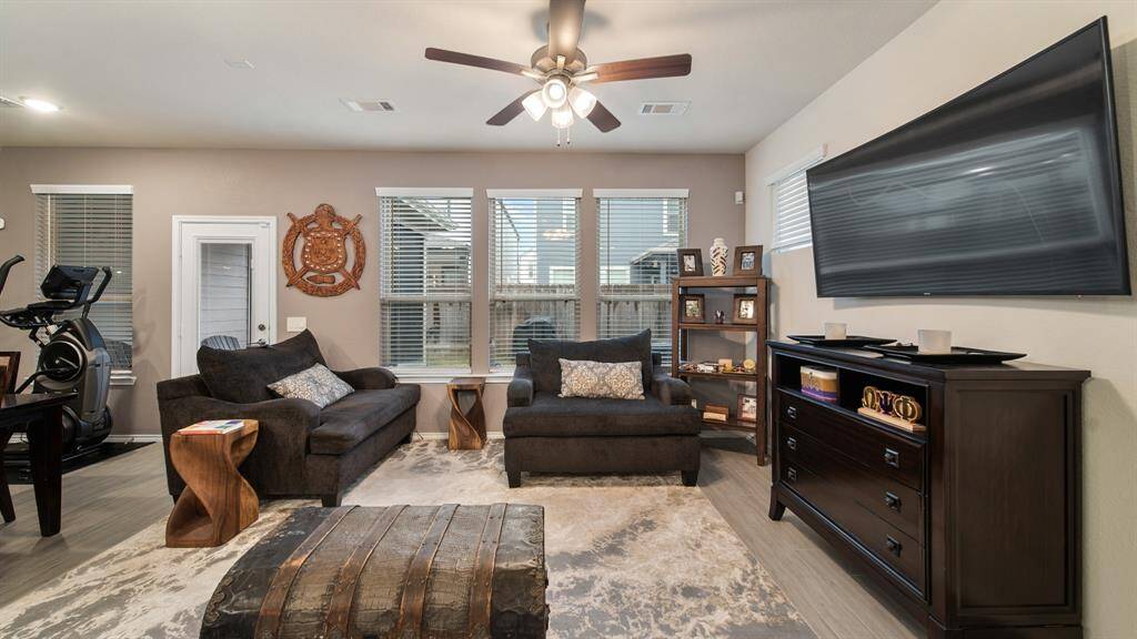 Living room features aceiling fan and a wallof windows.