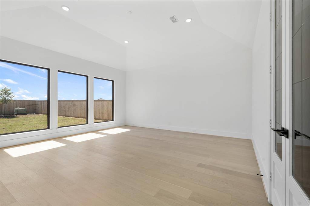 A spacious primary bedroom with large windows that flood the room with natural light, offering a serene and open retreat.