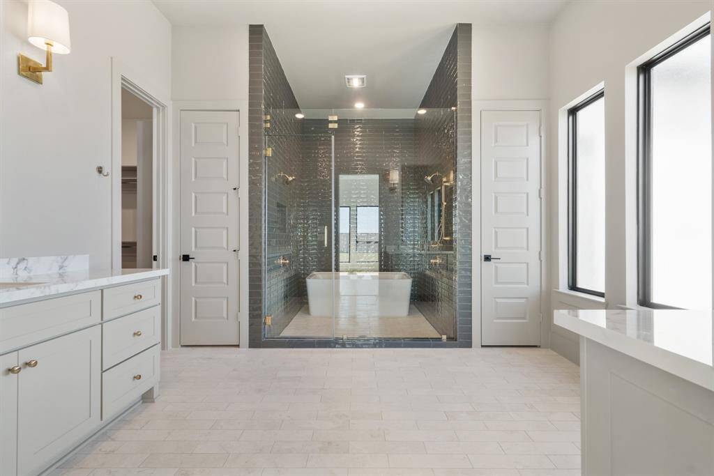 A sophisticated primary bathroom featuring a spacious shower with two showerheads and a freestanding tub, creating a relaxing and stylish space.