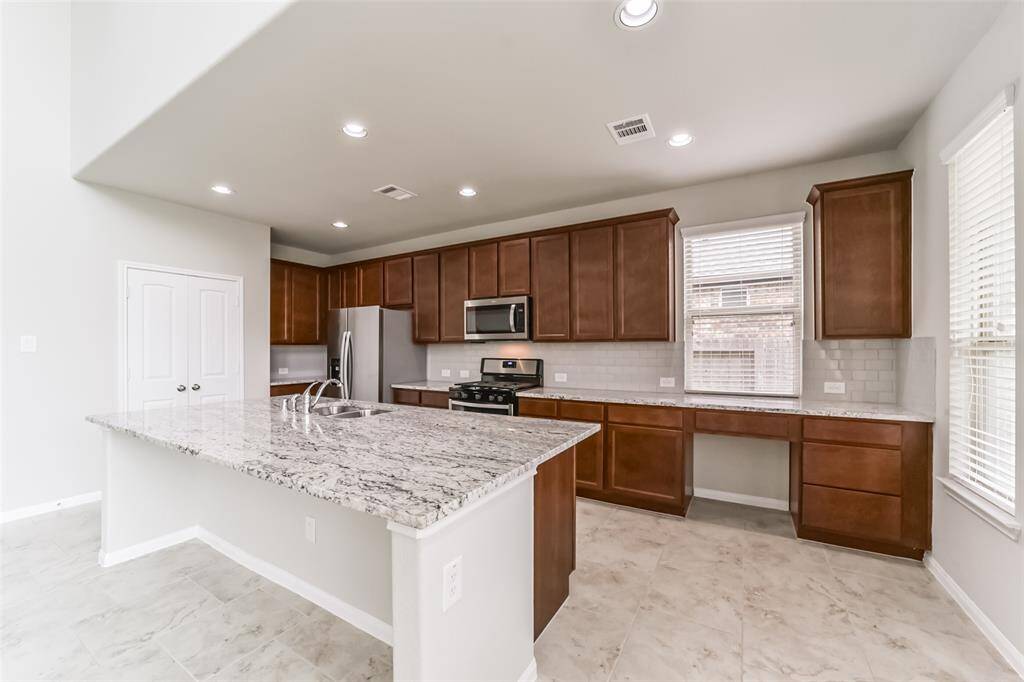 The island kitchen is charming and includes many pristine features such as top of the line stainless steel appliances with an gas range, and granite countertops.