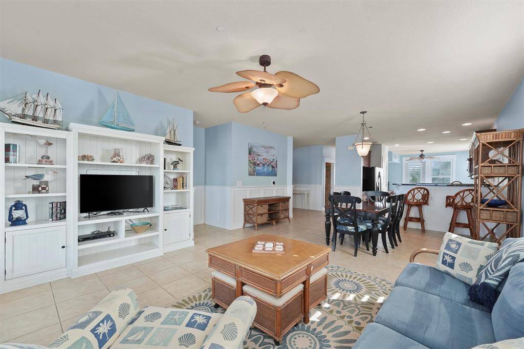 Seamlessly connected to the dining area and kitchen, this open-concept living room is perfect for hosting gatherings. The charming built-in shelving, adorned with nautical decor, adds character and complements the beachside ambiance.