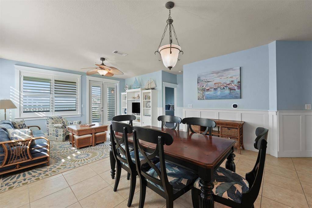 The open dining area offers a seamless flow to the living room, creating an inviting space for family meals or entertaining. The chic pendant lighting and classic wainscoting add an elegant touch to the coastal-inspired decor.