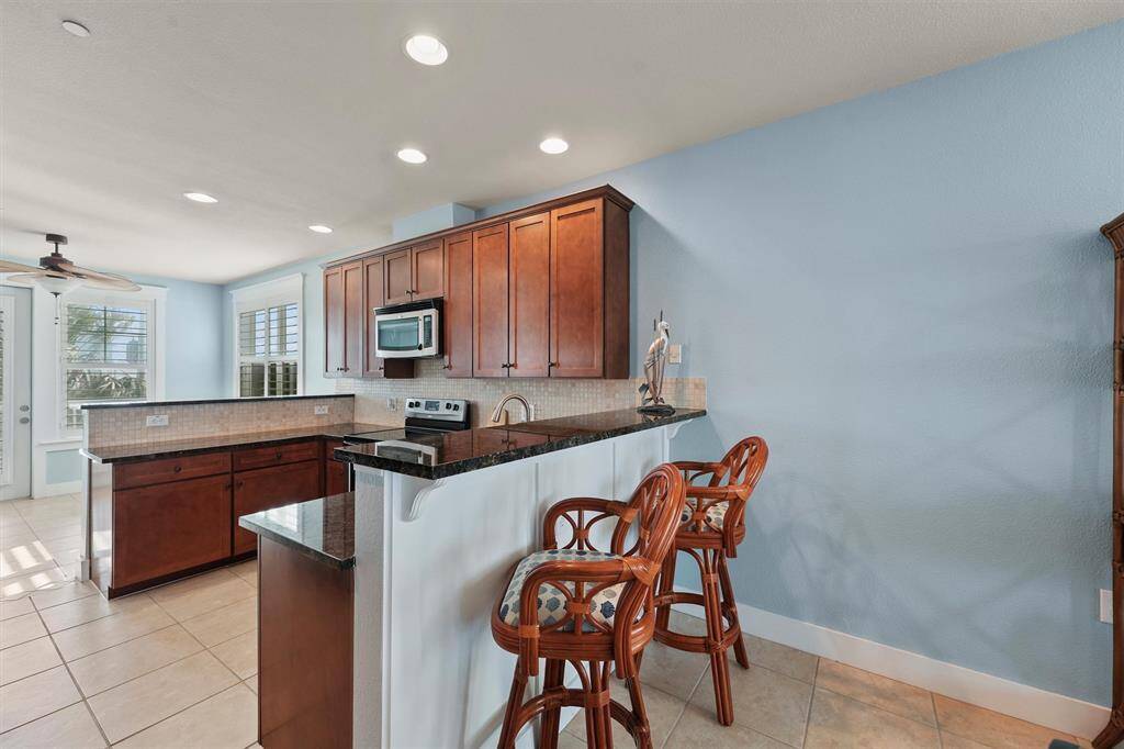 A cozy breakfast bar with rattan stools adds a touch of island charm to this kitchen, providing a casual spot for morning coffee or quick meals, with easy access to the nearby dining and living spaces.