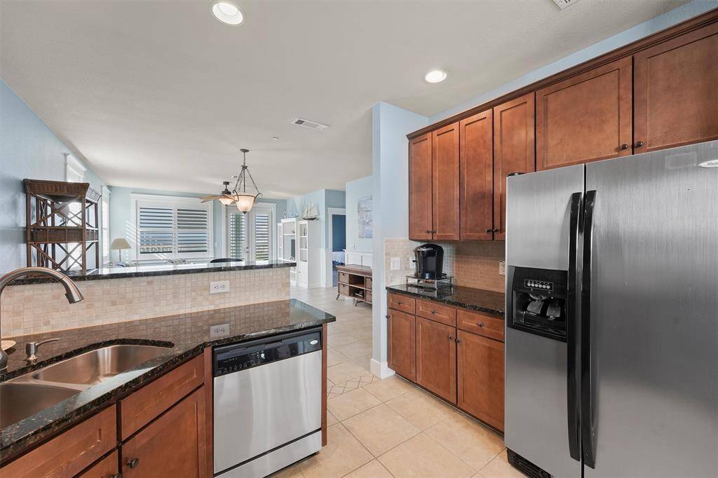 This stylish kitchen features rich wood cabinetry and granite countertops, creating a warm and inviting atmosphere. The open layout flows into the dining and living areas, perfect for effortless entertaining.
