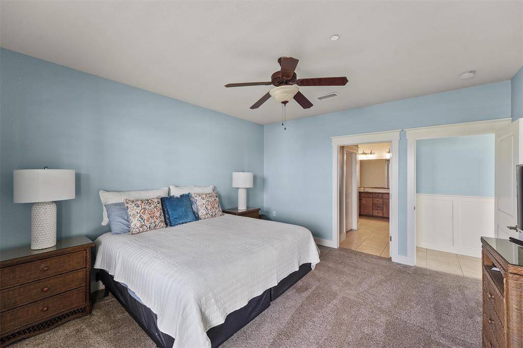 This inviting bedroom offers ample space for relaxation, with room for a large bed and nightstands. A ceiling fan adds a refreshing touch, perfect for winding down after a long day.