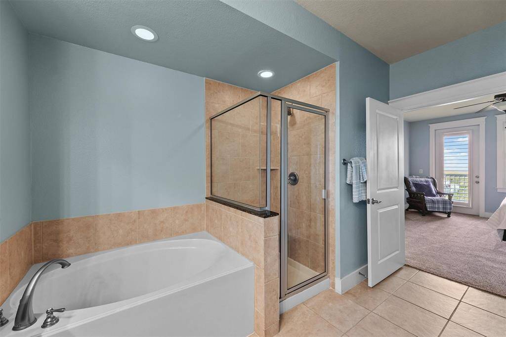Unwind in the luxurious soaking tub or enjoy the convenience of a glass-enclosed shower, set against warm tile accents that complete the spa-like ambiance of this elegant primary bathroom.