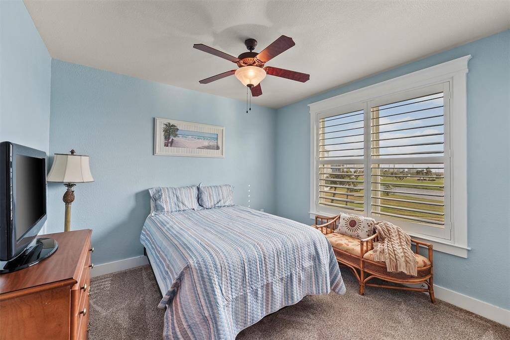 This serene guest bedroom offers a relaxing retreat with a large window that fills the space with natural light and frames views of the landscaped grounds.