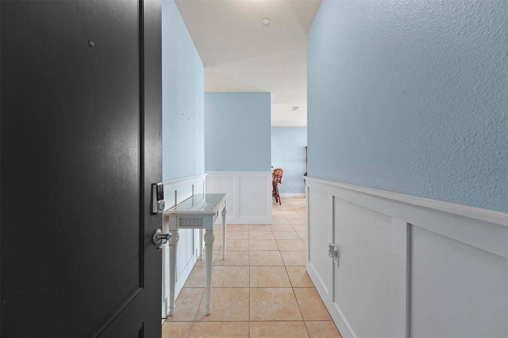 Step into a welcoming foyer featuring tasteful wainscoting and tiled flooring that guides you into the heart of the home, setting the tone for a warm and inviting atmosphere.