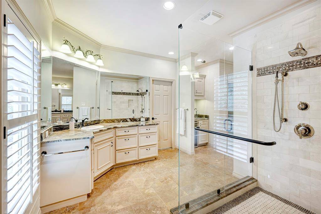 Primary bathroom has 2 separate exquisite "leather looking " counters. The tub was removed to make room for a spacious shower. The door next to the counter goes to Her spacious closet.  The "bar" area next to the closet door has a another sink and cooler.