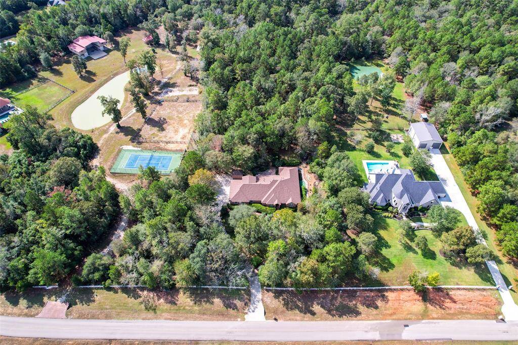 This aerial shot showcases the entire property, set on a beautifully landscaped lot in Grand Lake Estates. Nestled in a picturesque community, the home’s impressive size and outdoor features are highlighted, giving a sense of the privacy and natural beauty surrounding it.