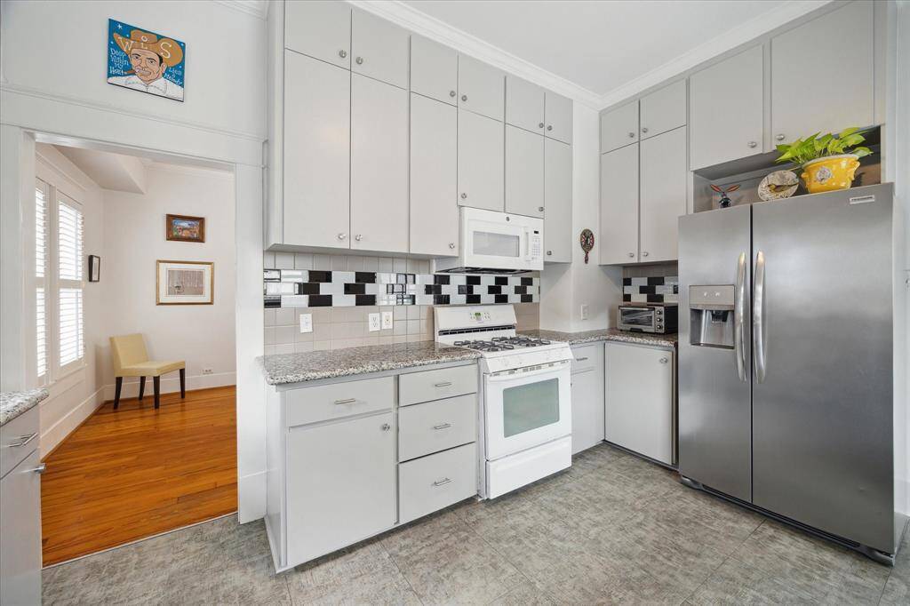 The kitchen features granite countertops, a beautiful tile backsplash, a gas oven/range, and cabinets that extend to the ceiling for excellent storage.  Notice the refrigerator/freezer that conveys with the home!
