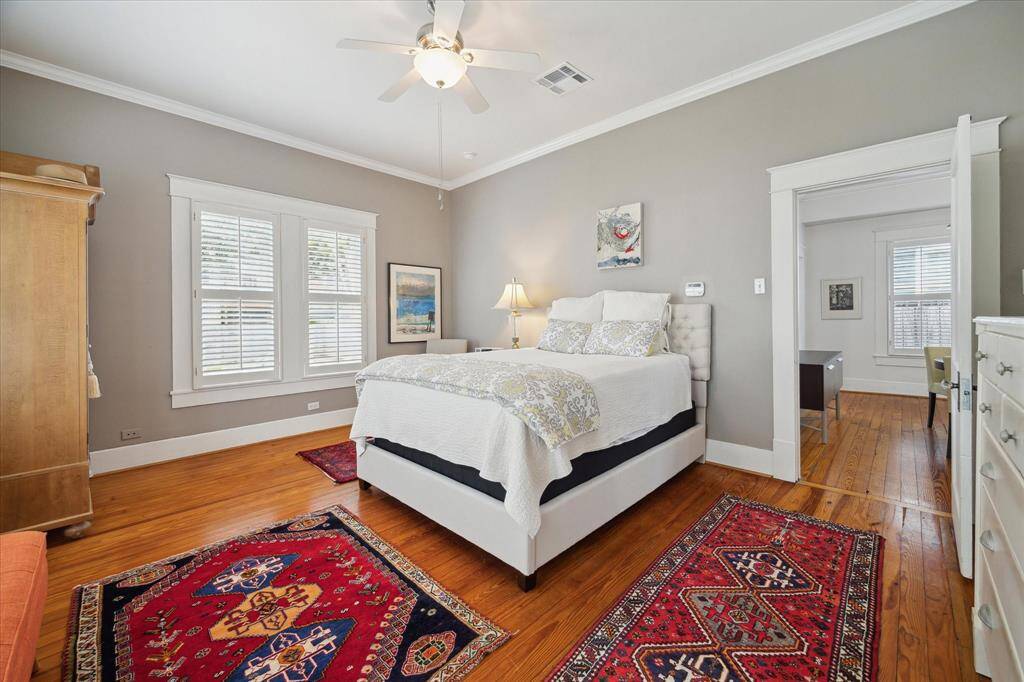 This lovely primary bedroom is enhanced by crown molding, ceiling fan and the tranquil, thoughtfully curated color palette creates a serene and welcoming retreat.
