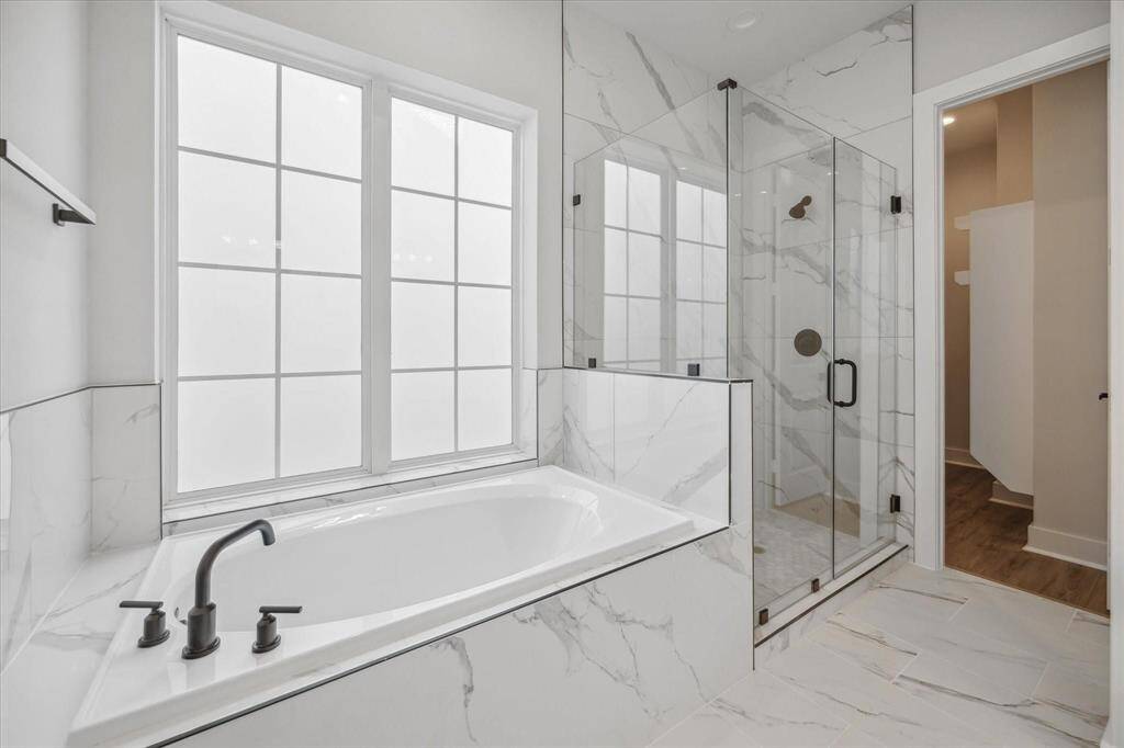 This primary bathroom offers a soaking tub, a large glass shower, double vanities and walk-in closet