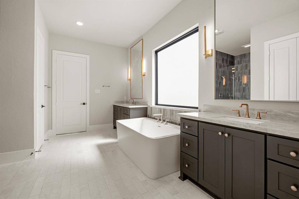 A stylish and serene primary bathroom featuring dual vanities, a sleek freestanding soaking tub, and high-end designer finishes throughout.