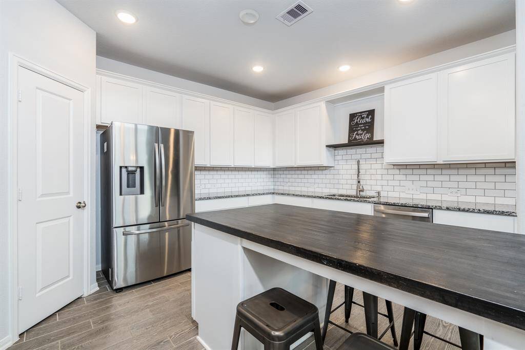 The kitchen boasts crisp white cabinets, subway tile backsplash, stainless appliances, granite countertops and a walk in pantry.