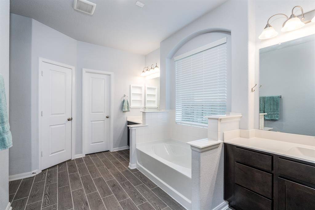 The elegant bath with wood tile flooring, garden tub and dual vanities offers the perfect retreat!
