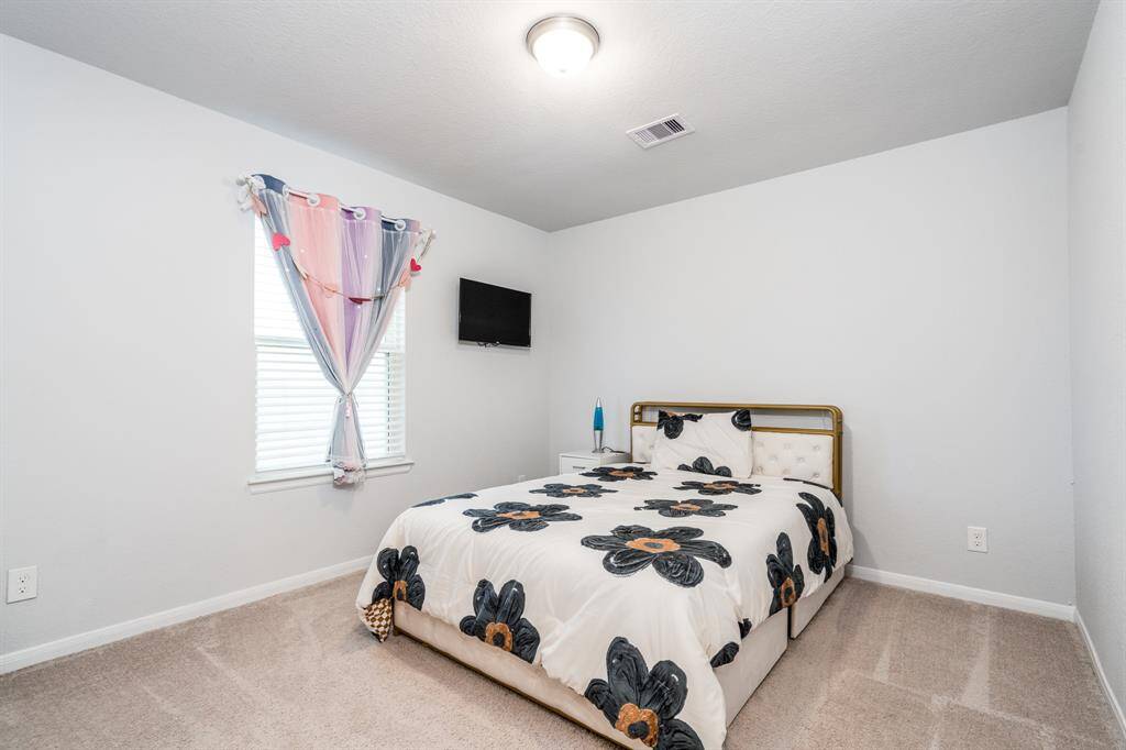The second of three secondary bedrooms offers neutral paint and carpet and walk-in closet.