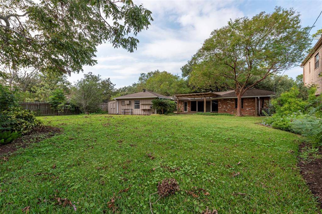 This is a single-story home featuring a spacious, green backyard with mature trees offering a tranquil outdoor living space.