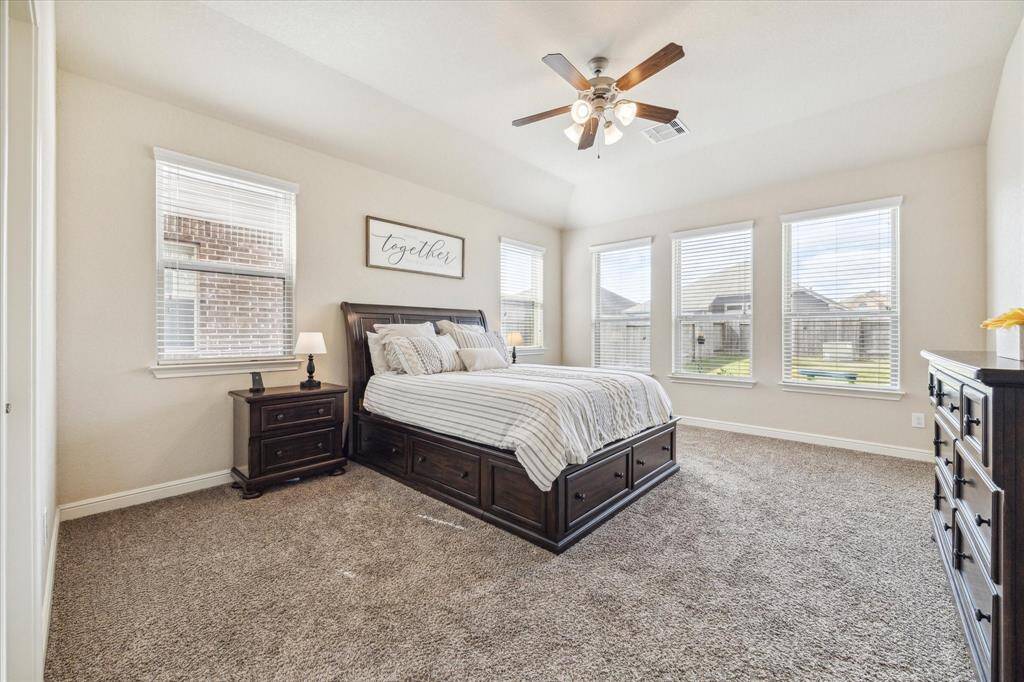 The Primary bedroom features a spacious layout with neutral walls and carpet, complemented by large windows that provide abundant natural light creating a cozy and inviting atmosphere.