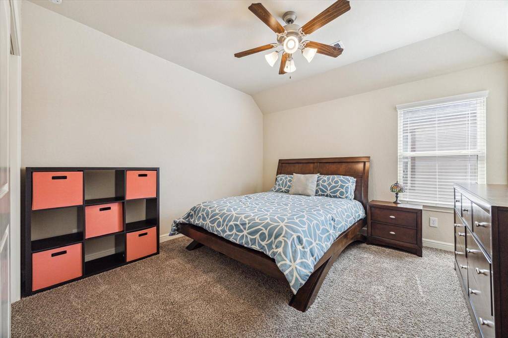 This cozy bedroom features a vaulted ceiling, a large window for natural light and lots of space for furniture.