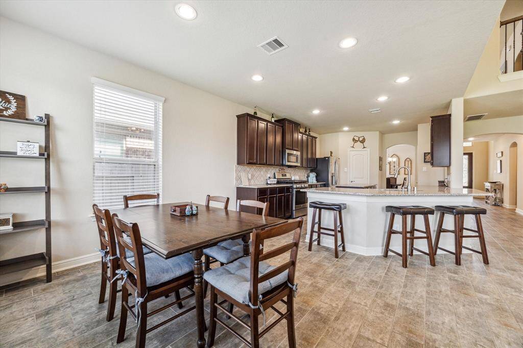 The spacious open-plan kitchen and dining area features dark wood cabinetry, modern appliances, and a large island with bar seating.