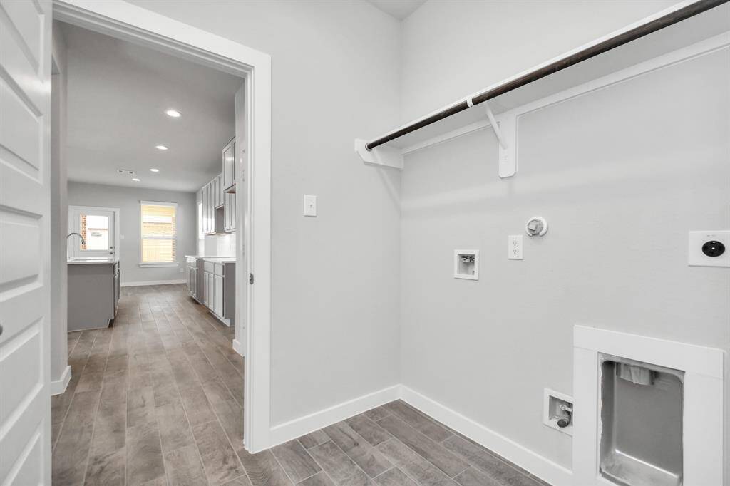 Located on first floor, a stylish laundry room where practicality meets a contemporary aesthetic. The dark finishes lend a sophisticated touch, creating a space that is both functional and visually appealing. Both electric and gas connections available. Sample photo of completed home with similar floor plan. As-built interior colors and selections may vary.