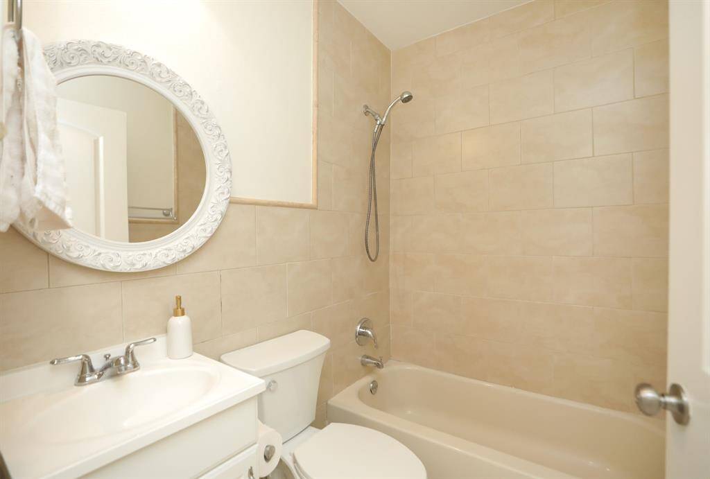 Secondary bathroom with tub shower, recent toilet and mirror.