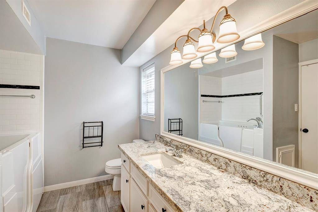 Full downstairs bathroom for the primary bedroom with granite counter and jetted walk-in tub.