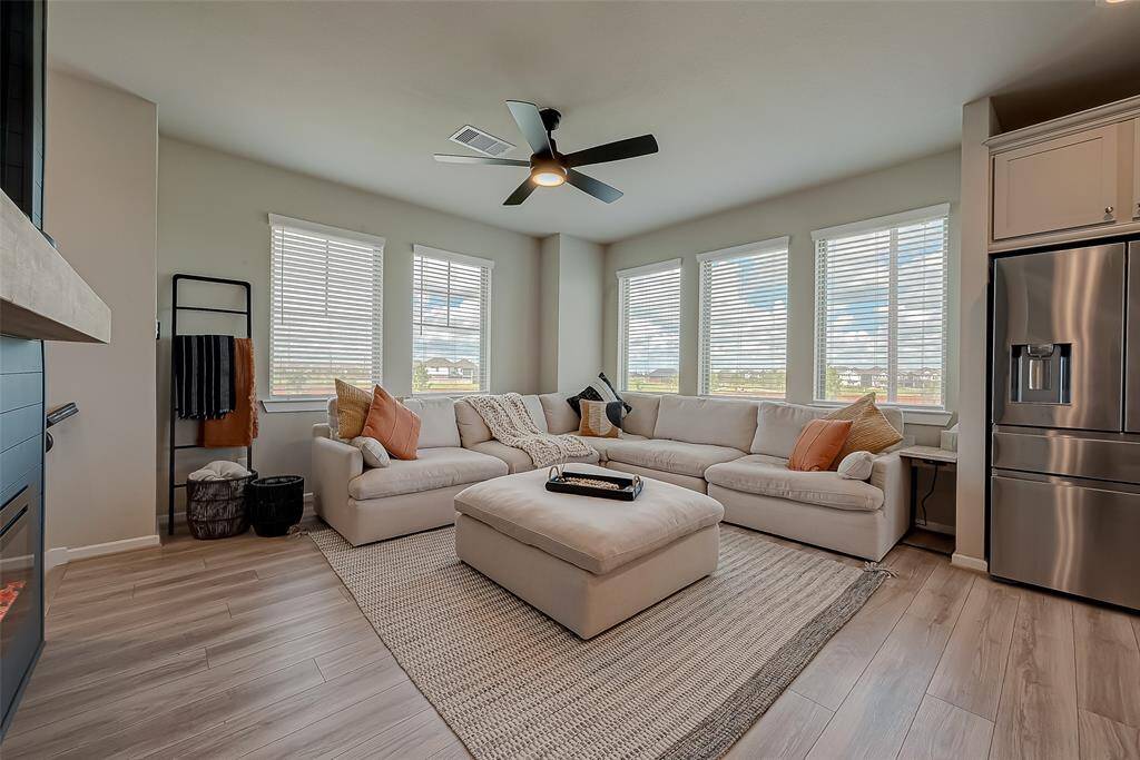 Experience the spacious living room on the second floor of this three-story home. Featuring ample lighting, sleek flooring with no carpet, and a stylish TV wall unit with an electronic fireplace, this inviting space is perfect for relaxation and entertainment.