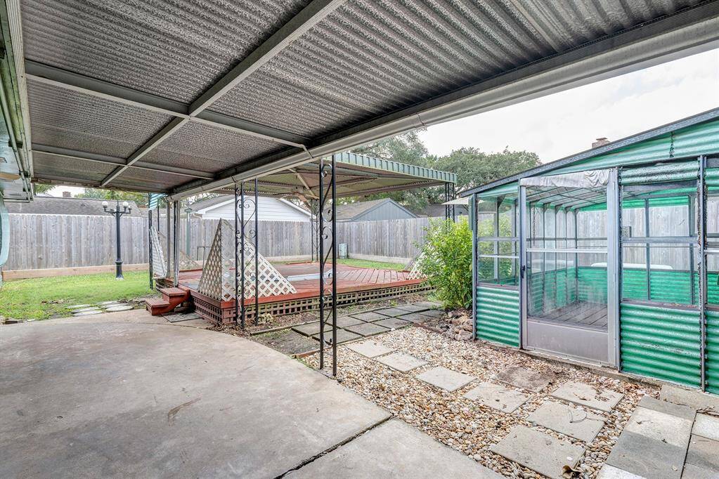 Covered backyard patio with greenhouse for the plant enthusiast.