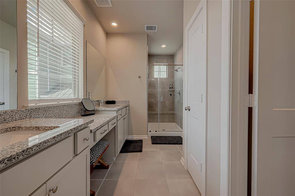 The full-size primary ensuite features a spacious shower, double sinks, and ample closet space. This luxurious bathroom offers modern amenities and elegant design, providing a perfect retreat for relaxation and convenience.
