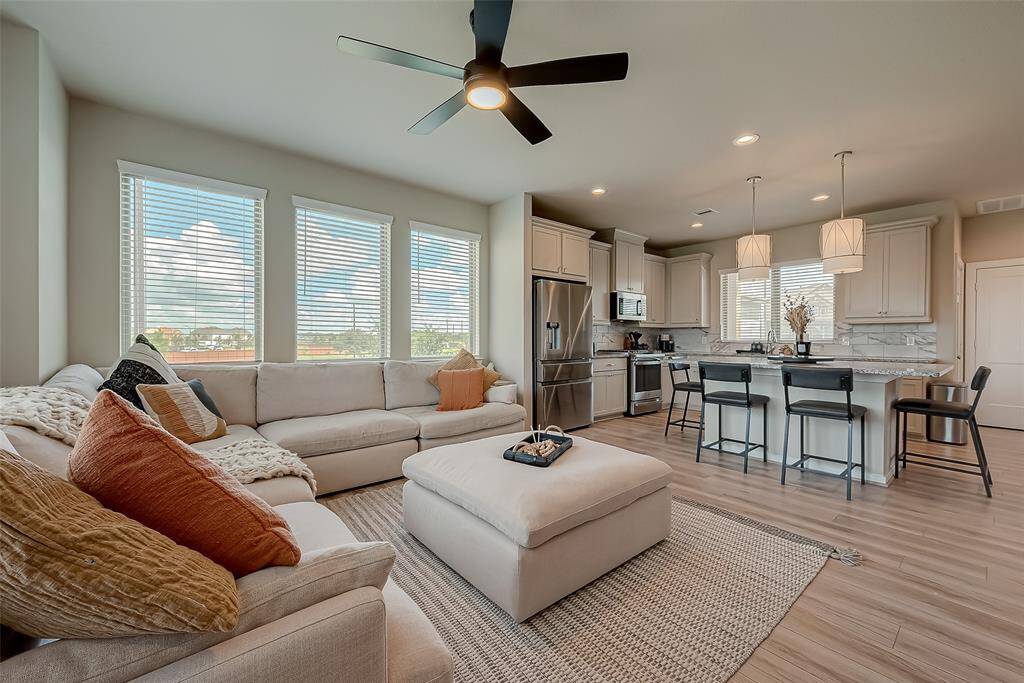 Experience the spacious living room on the second floor of this three-story home. Featuring ample lighting, sleek flooring with no carpet, and a stylish TV wall unit with an electronic fireplace, this inviting space is perfect for relaxation and entertainment.