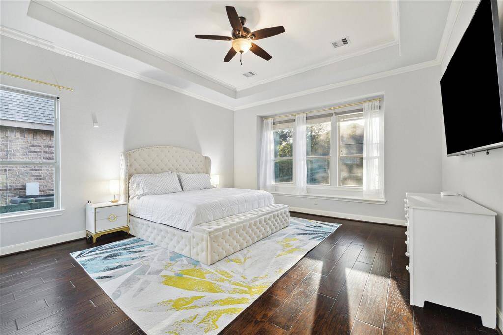 An alternate view highlights the openness of the primary bedroom, with large windows that flood the room with natural light, creating a bright and airy atmosphere. The generous space offers a tranquil retreat, perfect for relaxation while enjoying the warmth and beauty of the daylight.