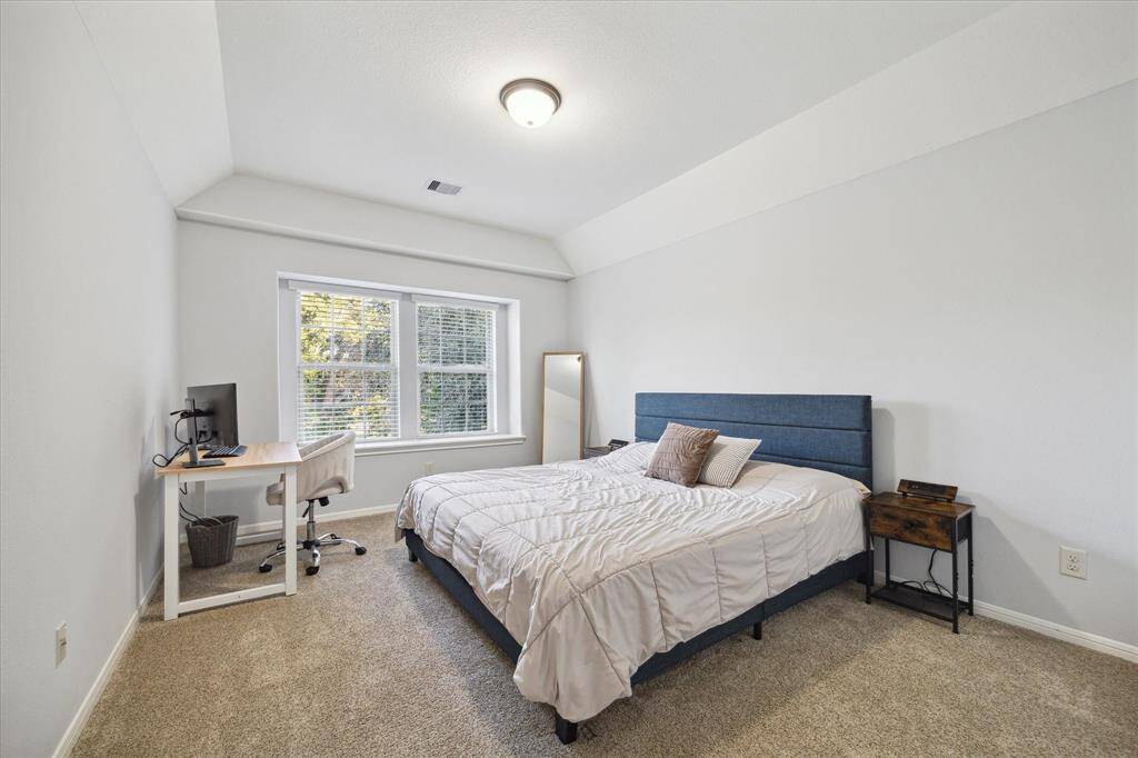 This upstairs secondary bedroom offers cozy comfort and includes a large window that brings in natural light, creating a warm and inviting space.