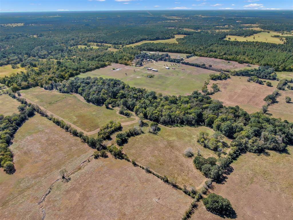 This aerial photograph showcases a 101.293-acre property with a mix of open fields, patches of trees, and agricultural land, offering a rural setting with ample space for privacy and outdoor activities.