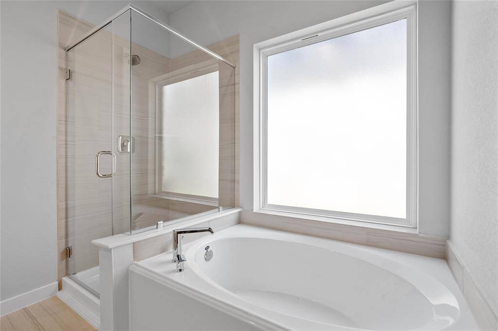 This primary bathroom is definitely move-in ready! Featuring a framed walk-in shower with tile surround, separate garden tub for soaking after a long day!