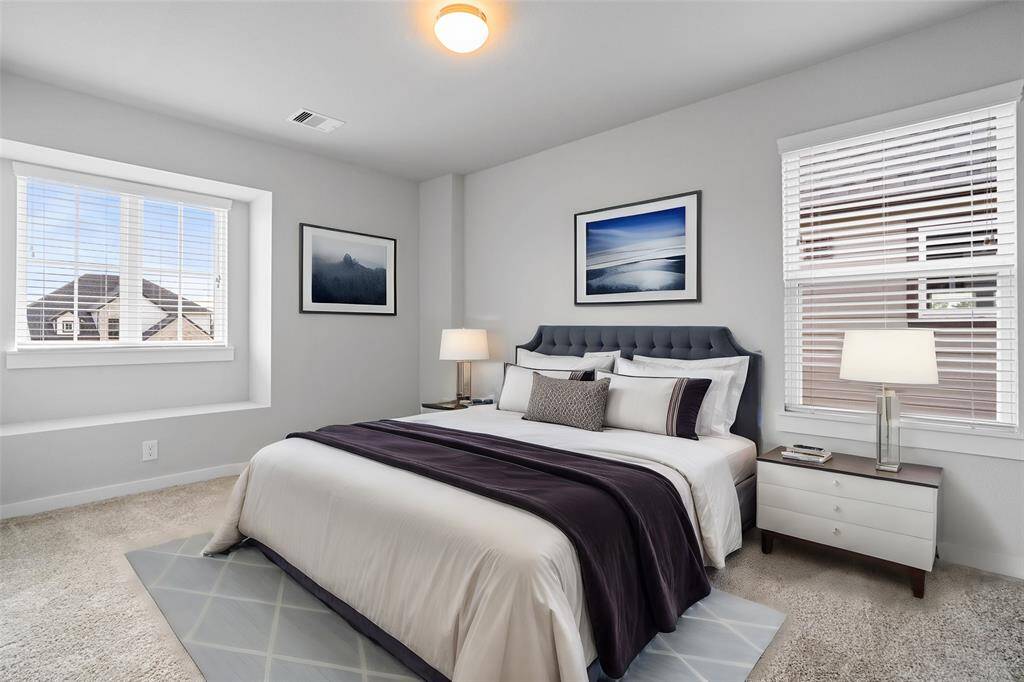 Secondary bedroom features plush carpet, custom paint, high ceilings, and a large window with privacy blinds.