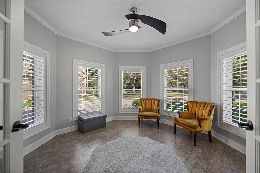 French doors lead into the office at the front of the home with plenty of windows & natural lighting. Beautiful crown molding and window trim detail complement the plantation shutters. Wood-like tile flooring and a modern ceiling fan.