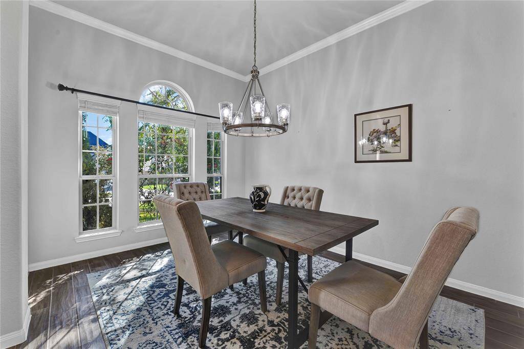 Bright dining room with large windows, elegant chandelier, and a cozy, modern decor.