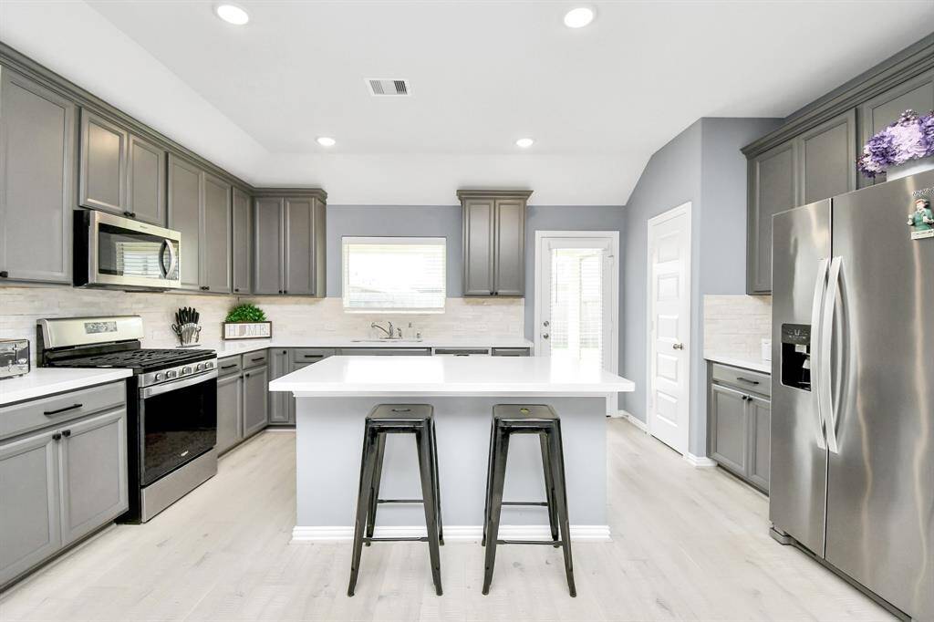 The stunning kitchen boasts stainless steel appliances, striking tile backsplash areas and elegant quartz countertops - combining luxurious style and functionality to create the perfect culinary space!