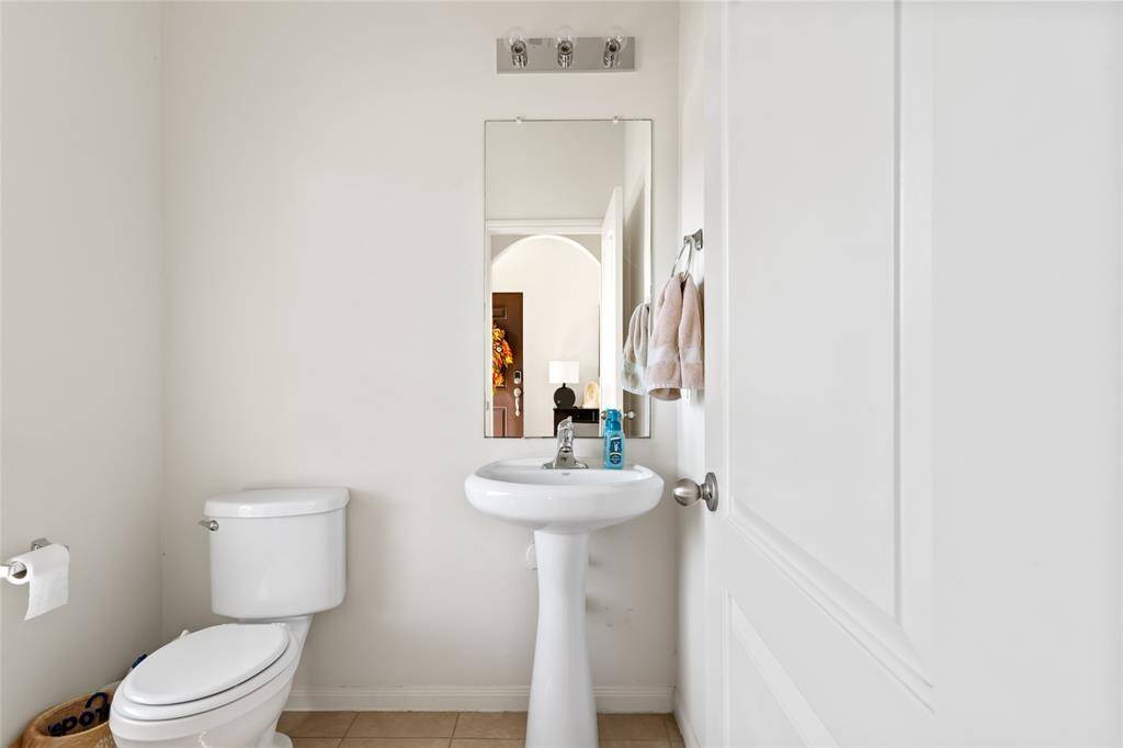 A stylish half bath offers convenience and comfort with a sleek design. Featuring a toilet and a vanity with a sink, it’s a functional space perfect for guests, providing a clean, private retreat on the main floor.