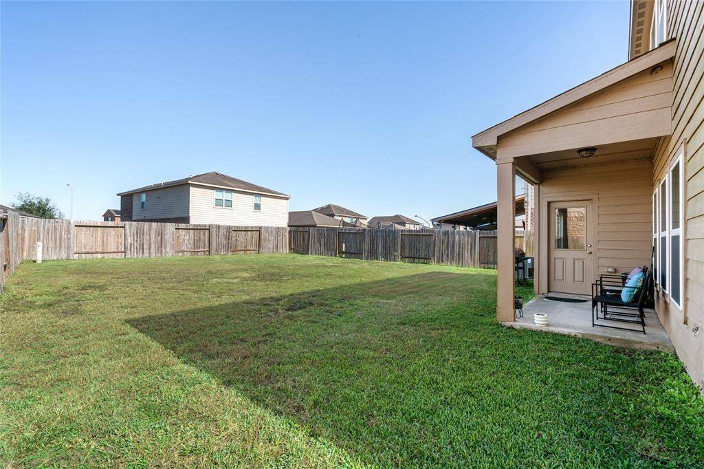 This cozy backyard features a small covered patio, creating a perfect spot for shaded relaxation. The compact outdoor space is ideal for a bistro set or small gathering, offering just the right blend of comfort and privacy.