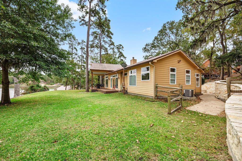 A charming stone wall pathway leads from the front of the property to the backyard on Lake Livingston, passing through an extra-wide entrance gate and continuing beyond for a seamless blend of elegance and lakeside living.