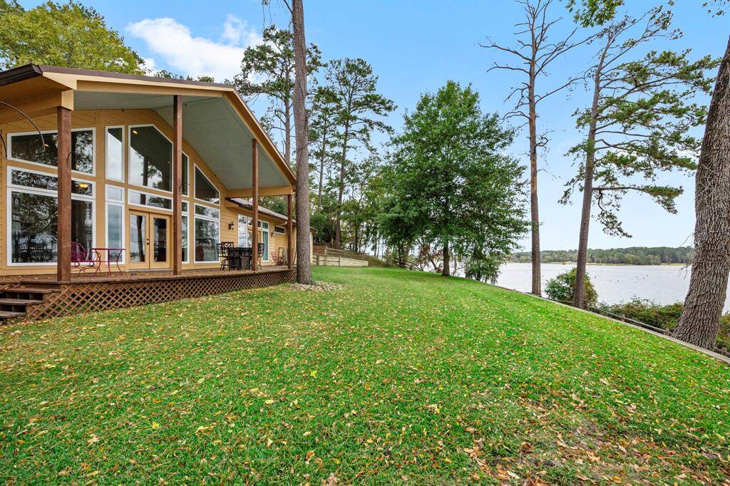 The expanded back porch stretches nearly the entire length of the home, offering panoramic views of the Lake Livingston waterfront and creating a seamless indoor-outdoor living experience.