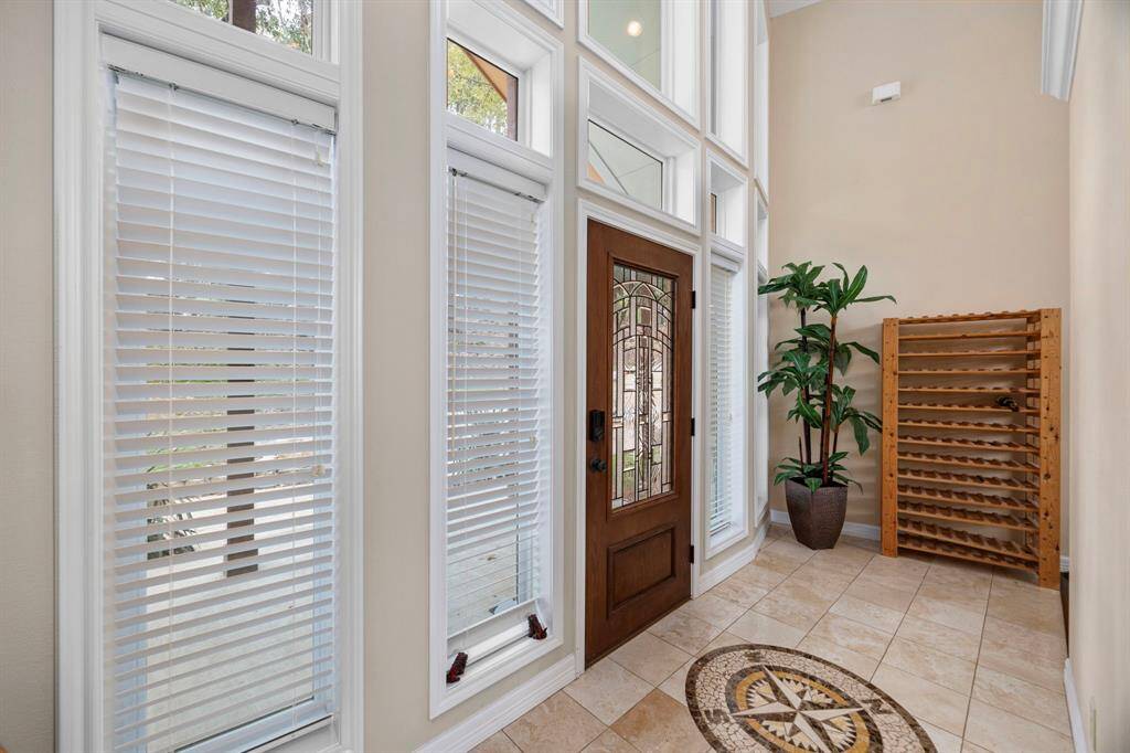 The front entrance welcomes you with soaring high ceilings and elegant tile flooring, featuring a striking compass design that sets a creative tone for the home.