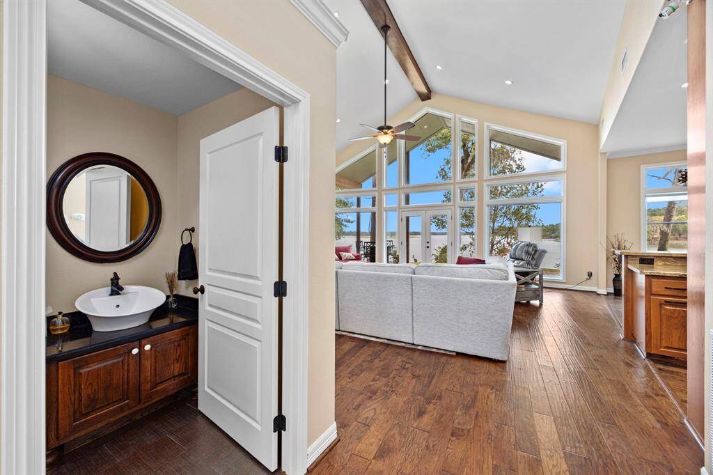 As you step inside the front entrance, a convenient stand-alone half-bath greets you in the foreground, perfect for guests. Beyond, the spacious family room draws your eye to a wall of windows showcasing stunning views of the Lake Livingston waterfront.