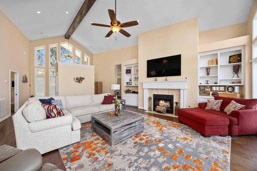 The family room features high ceilings, a cozy fireplace, and built-in bookshelves with cabinets, combining warmth and elegance as it opens toward the heart of the home.